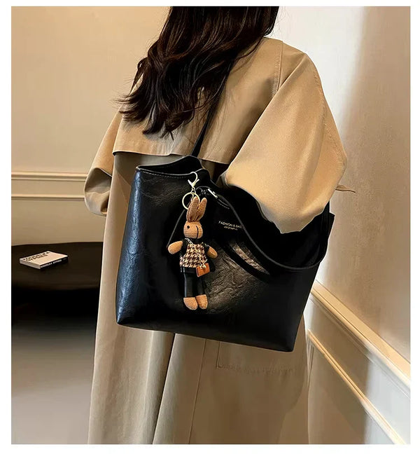 Sac à main femme noir élégant, porté à l’épaule avec manteau beige