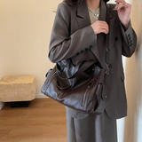 Sac noir AUDREY tenu à la main, ambiance élégante