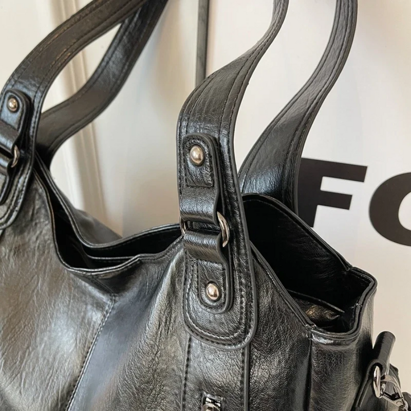 Sac noir porté à l’épaule avec pantalon blanc, look casual